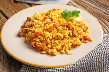 Plate with tasty pilaf on wooden background, closeup