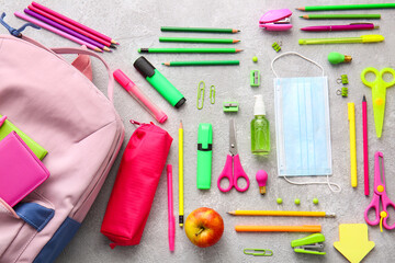 School backpack and stationery on light background