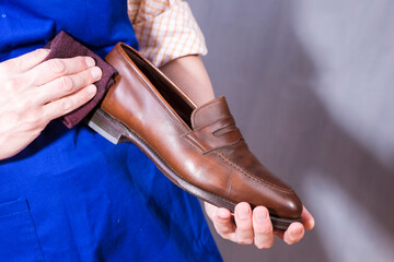Male Shoes Cleaner with Cloth For Brown Leather Penny Loafers Shoes While Cleaning in Workshop.