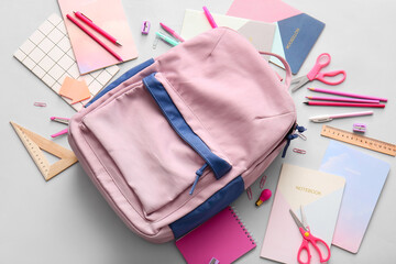 School backpack and stationery on light background