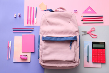 School backpack and stationery on color background