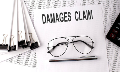 DEMAGES CLAIM text on paper with chart and office tools , business concept