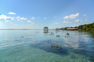 Fototapeta na wymiar Bacalar Lagoon at Mexico Caribbean. Cabins for swimming in the turquoise freshwater of the lake. Touristic and tropical travel destination. Tropical vacation background with copy space.