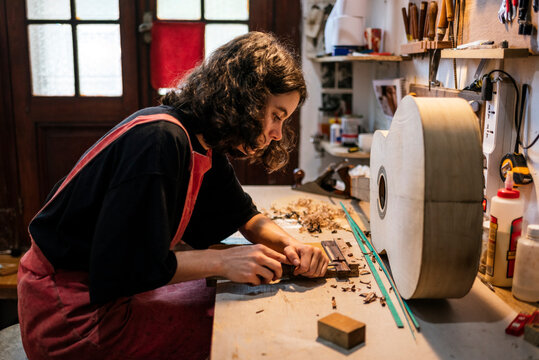 woman luthier making guitars in her musical instrument workshop