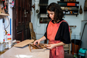 woman luthier making guitars in her musical instrument workshop