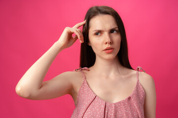 Fototapeta premium Portrait of young woman thinking and wonder against pink background