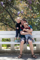 Happy candid family in park. Young father is having fun with two small daughters outdoors in summer