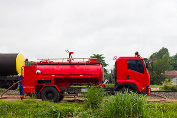 A red fire truck is waiting near the railroad tracks.