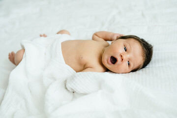 Cute one week old baby boy portrait. New born baby girl lying on blanket, looking at camera.