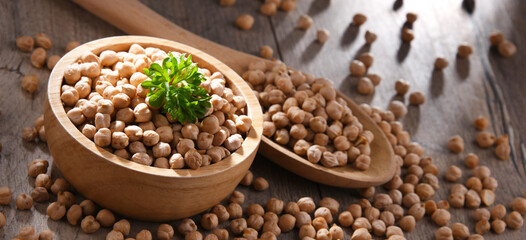 Fototapeta premium Bowl and spoon of chickpeas on wooden table
