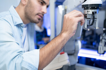 Focus of young Caucasian male engineers hand touching and checking automation robotic arm machine...