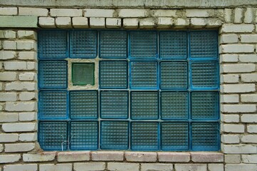 Blue glass window in white brick wall
