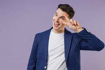 Humorous young successful employee business man corporate lawyer 20s wears formal blue suit white t-shirt work in office cover eye by victory sign isolated on pastel purple background studio portrait.