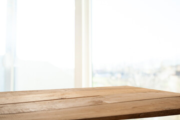 Empty table top made of natural wood, light rays from the window on the background of the wall. For product demonstration and installation