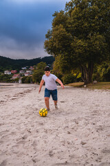 Niño en la playa jugando al futbol con un balón amarillo en la playa © Mac Estudio