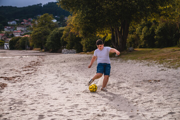 Niño en la playa jugando al futbol con un balón amarillo en la playa © Mac Estudio