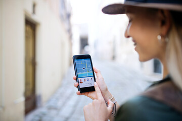 Young woman traveler with smartphone in city on holiday, car sharing concept.