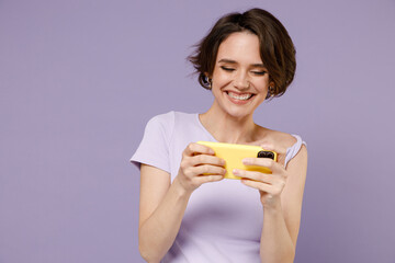 Young smiling gambling happy woman 20s wearing white t-shirt using play racing app on mobile cell...