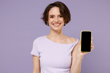 Young smiling satisfied cheerful happy brunette woman with bob haircut in white t-shirt using mobile cell phone with blank screen workspace area isolated on pastel purple background studio portrait