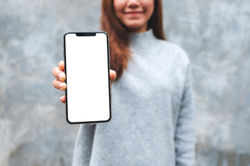 Mockup image of a beautiful woman holding and showing mobile phone with blank white screen