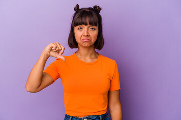 Young mixed race woman isolated on purple background showing a dislike gesture, thumbs down....