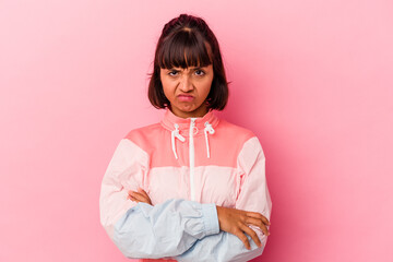 Young mixed race woman isolated on pink background frowning face in displeasure, keeps arms folded.