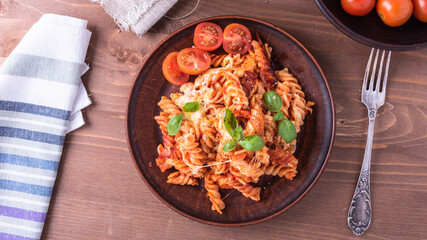 Italian baked pasta - fusilli in tomato sauce with cheese and cheri tomatoes on a plate, top view, flat lay