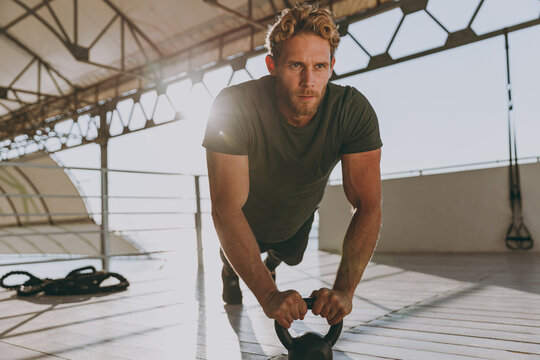 Full body young masculine strong sporty athletic fit sportsman man wear sports clothes warm up training work out engaged with kettlebell at outdoor gym sea beach outdoor seaside in summer day morning. - Powered by Adobe
