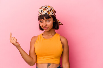 Young mixed race woman isolated on pink background pointing with finger at you as if inviting come closer.