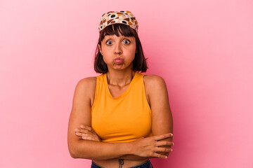 Young mixed race woman isolated on pink background blows cheeks, has tired expression. Facial...