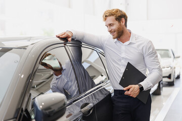 Man minded customer male buyer client in white shirt hold clipboard paper document lean on car...