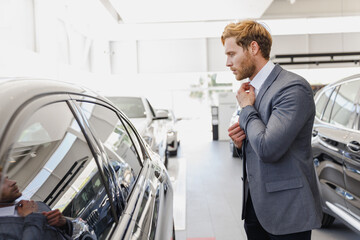 Man happy customer businessman male buyer client 20s wearing classic grey suit choose auto wants to buy new automobile car in showroom vehicle salon dealership store motor show indoor Sale concept
