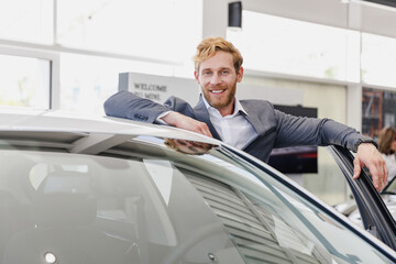 Happy man customer male buyer businessman client wear classic suit get out car chooses auto wants buy new automobile in showroom vehicle salon dealership store motor show indoor Car sales concept