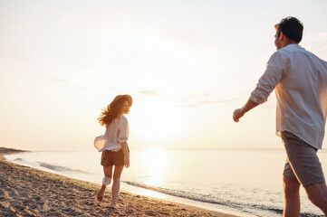 Back rear view young joyful couple two friends family man woman in white shirt clothes hold hands...