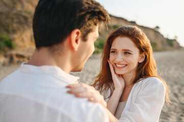 Satisfied happy excited young couple two friends family man woman in white clothes hold face meet each other enjoy together at sunrise over sea beach ocean outside seaside in summer day sunset evening