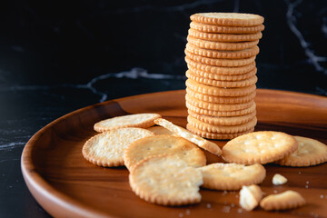Stacked salt crackers on wooed plate as black background