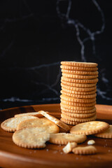Stacked salt crackers on wooed plate as black background