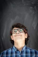 Teenage boy with glasses in front of classroom chalkboard
