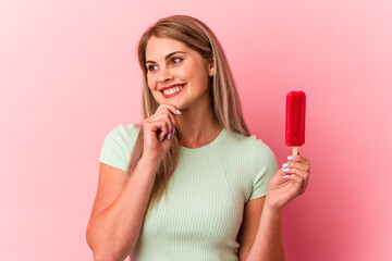 Young russian woman holding an ice cream isolated on pink background looking sideways with doubtful and skeptical expression.