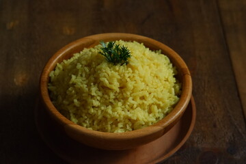 a bowl of  yellow rice on a wooden table 