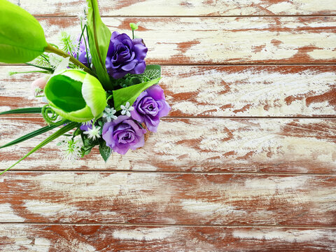 Purple flowers in a vase set on a beautifully patterned wooden table.