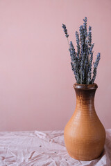 Floral home interior decor. Dry lavender flowers in a vase on a pink background.