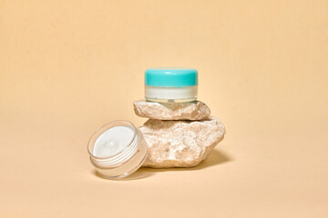Cosmetics container on the pastel background. Natural stones. Earth colors, zero waste containers. Mockup concept. Copy space for text or design. Can be used as advert banner.