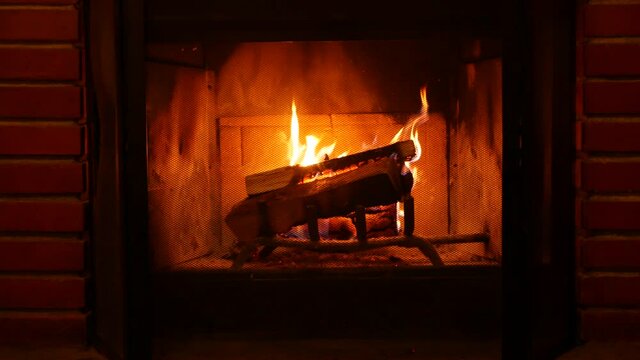 Fire in brick fireplace, firewood burning, wood blazing in cozy lodge, hut or cabin. Romantic weekend on winter holidays, fireside in warm cosy cottage house. Seamless looped cinemagraph background.
