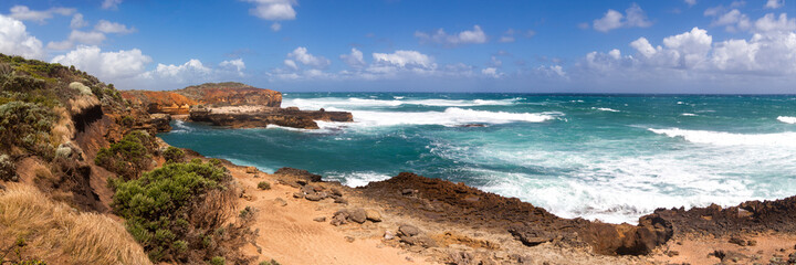 Colorful bright panorama of the vast ocean, turquoise large waves and empty sandy beach in the sea near the coastal cliffs. Port Campbell. Twelve Apostles.