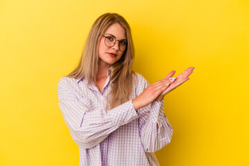 Young russian woman isolated on yellow background feeling energetic and comfortable, rubbing hands confident.