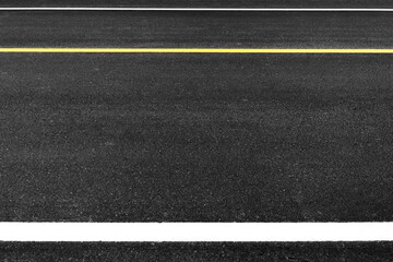 Close up black asphalt road surface texture with a separation yellow and white line.