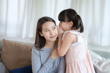 Fototapeta na wymiar Asian mother feel happiness during playing her cute daughter with love and care at home