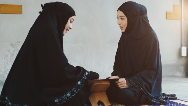 Portrait of an Asian Muslim women in a daily prayer at home reciting Surah al-Fatiha passage of the Qur'an in a single act of Sujud called a Sajdah or prostration