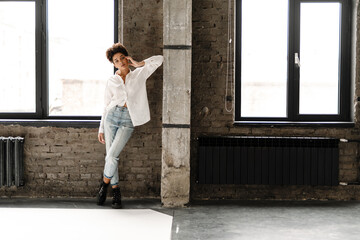 Young black woman leaning on wall and looking at camera